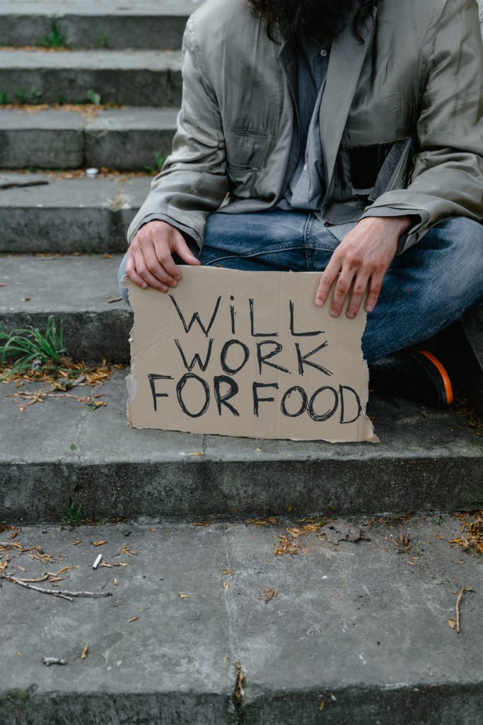 Man holding a sign that says "Will Work for Food"